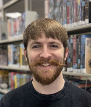 Headshot of Kasen Urhammer, Marketing & PR Manager, smiling in front of bookshelves.